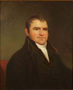 White man  with short brown hair, wearing a dark coat, high-necked vest, and white cravat.